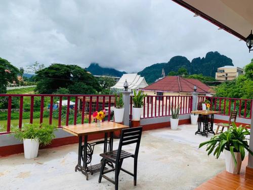un patio con 2 mesas y sillas en un balcón en Inthila Garden Guest House en Vang Vieng