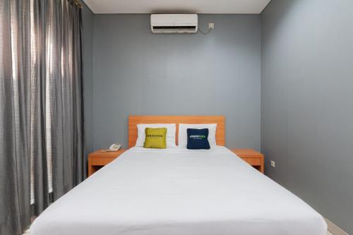 1 dormitorio con 1 cama blanca grande y 2 almohadas en RedDoorz Plus near Kelapa Dua Kebon Jeruk, en Yakarta