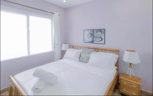 ein weißes Bett in einem Zimmer mit Fenster in der Unterkunft Executive 2 bedroom Apartment At East Legon in Accra