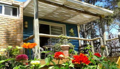 a house with a pergola and flowers in front of it at Il Tano Suites in Punta Del Diablo