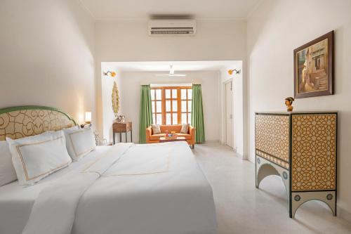 a bedroom with a large white bed and a couch at Gaj Kesri by 7Apple Resorts in Bikaner