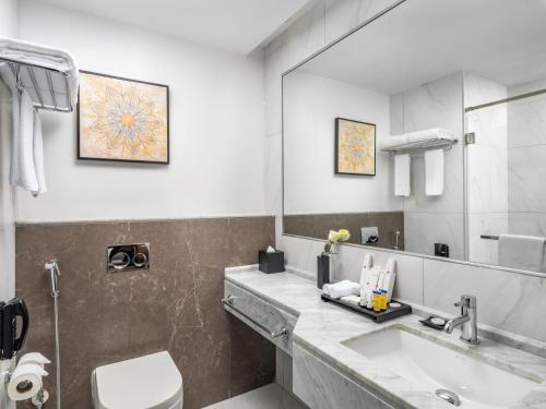 La salle de bains est pourvue d'un lavabo, de toilettes et d'un miroir. dans l'établissement Wirgan Hotel Al Nour, à La Mecque