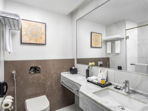 a bathroom with a sink and a toilet and a mirror at Wirgan Hotel Al Nour in Makkah