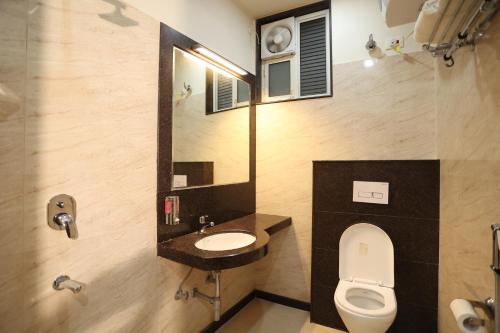 bagno con servizi igienici, lavandino e specchio di Royal GM Plaza a Jaipur