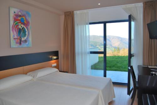 Una habitación de hotel con una cama y una ventana grande. en Hotel Parrilla el Zangano, en Boal