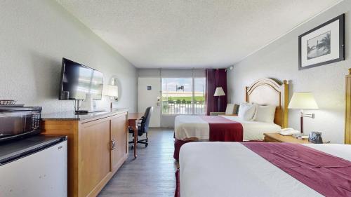 a hotel room with two beds and a flat screen tv at Days Inn by Wyndham Orlando Downtown in Orlando