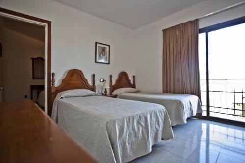 a hotel room with two beds and a balcony at Hotel Beri in Llança