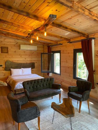 a bedroom with a bed and a couch and two chairs at Tepe Dağ Evleri in Çamlıhemşin
