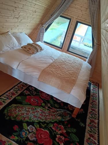 a bed in a small room with a window at Carpatina A-Frame Retreat - Rustic Cabins for Couples in Runcu