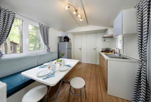 a small kitchen with a white table and chairs at Albatross Mobile Homes on Camping Bella Austria in Sankt Peter am Kammersberg