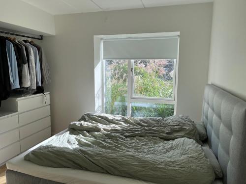 1 cama no hecha en un dormitorio con ventana en Charming Aalborg Apartment With parking en Aalborg