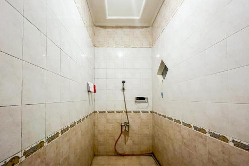 a shower with a hose in a tiled room at RedDoorz Syariah At Santana Stasiun Kepanjen in Malang