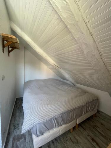 a white bed in a room with a roof at La bergerie in Roubion