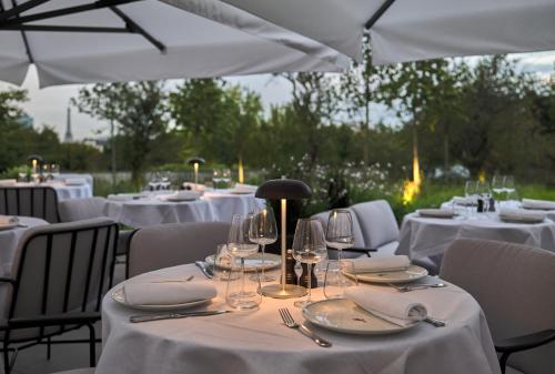 a group of tables with white table linen and wine glasses at Domaine de la Reine Margot Paris-Issy - MGallery Collection in Issy-les-Moulineaux