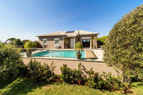 a house with a swimming pool in a yard at Villa avec piscine vue mer et montagne visite à la ferme in Saint-Joseph