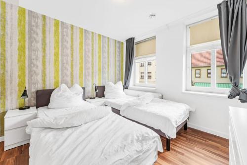 two beds in a room with two windows at Cosy apartment with balcony and fireplace in Jüterbog
