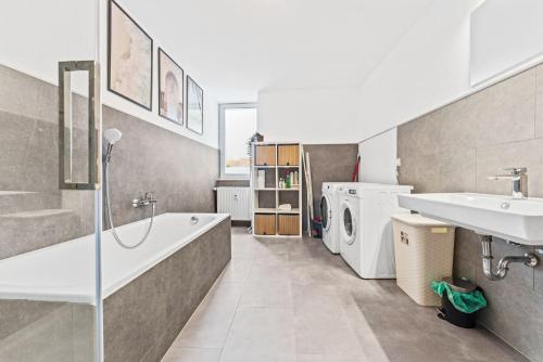 y baño con bañera, lavabo y lavadora. en Cosy apartment with balcony and fireplace en Jüterbog