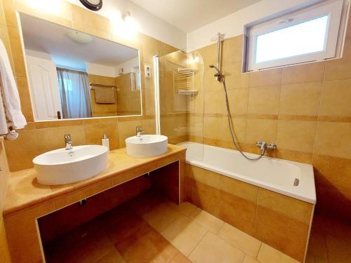 a bathroom with two sinks and a tub and a mirror at Lexi Jakuzzis Apartman Balatonboglár in Balatonboglár