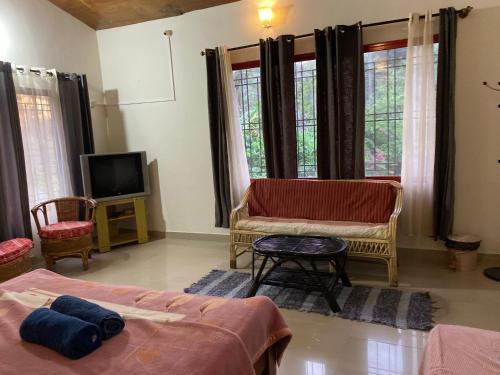 a living room with two beds and a tv at Coorg Sai Estate Ecobreeze Homestay in Madikeri