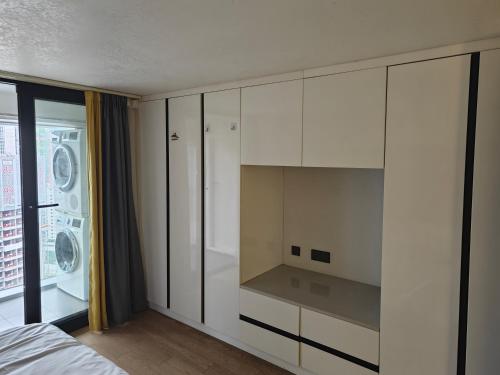 a bedroom with white cabinets and a bed and a window at Xinghe Times Apartment - Shenzhen North Railway Station in Shenzhen