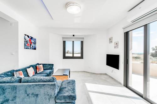 a living room with a blue couch and a tv at Villa Elpida THREE by Ezoria Villas in Timi, Paphos in Paphos