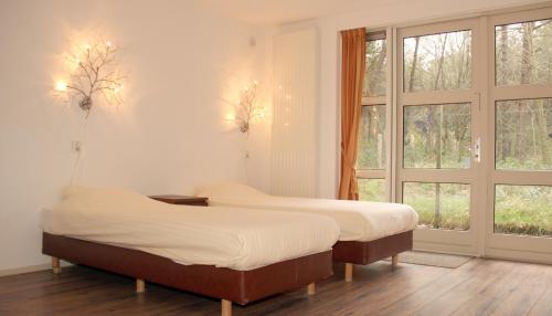 two beds sitting in a room with windows at Hotel Studio Bosch Duin Strand in Den Helder