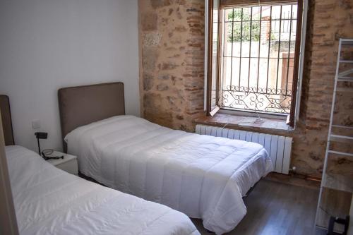 two beds in a room with a window at La Casona de 1717 in El Burgo de Osma