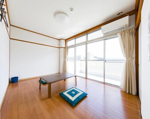 een woonkamer met een tafel en een groot raam bij ゲストハウスシティ in Hitoyoshi