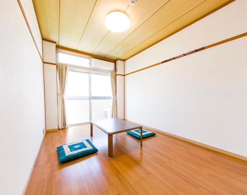 een lege kamer met een tafel en een raam bij ゲストハウスシティ in Hitoyoshi