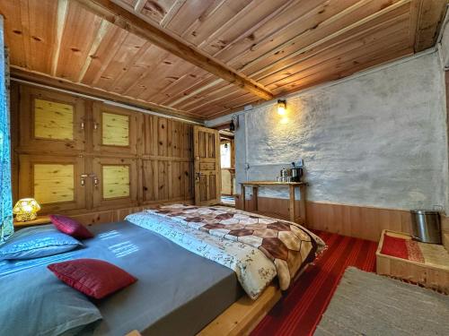 a large bed in a room with wooden walls at The Misty Wilds Home, Jibhi in Jibhi