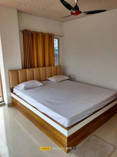 a bedroom with a large bed with a wooden headboard at Mayer Anchal in Bāghdogra