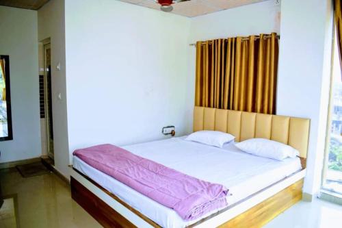 a bed in a room with a large window at Mayer Anchal in Bāghdogra