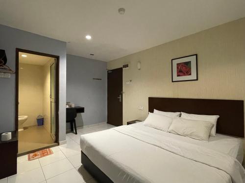 a bedroom with a large white bed and a bathroom at M Three Hotel by SECOMS in Kampong Batu Tiga