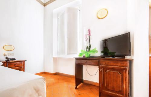una camera da letto con TV su un comò in legno di Hotel Costantini a Firenze