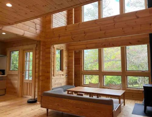 a living room with a table and some windows at 【moi】山中湖 新築フィンランドログハウス 大自然の中でBBQ可 in Yamanakako