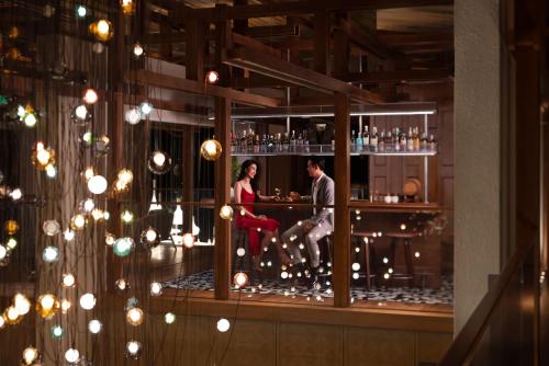 a man and a woman sitting at a bar at New World Hoiana Beach Resort in Hoi An