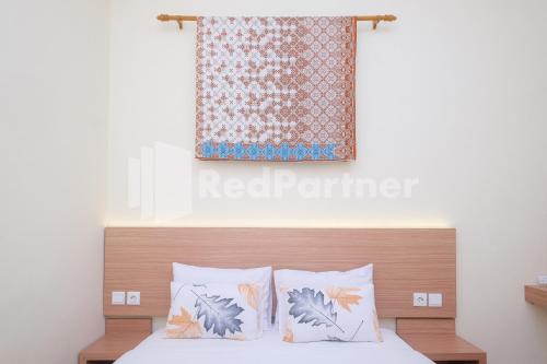 a bedroom with a bed with two pillows and a curtain at Ndliman House near UGM Jogja Mitra RedDoorz in Kejayan