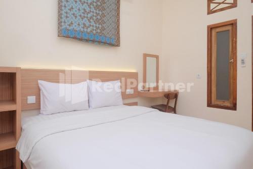 a bedroom with a large white bed and a mirror at Ndliman House near UGM Jogja Mitra RedDoorz in Kejayan