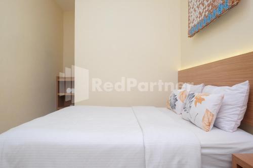 a bedroom with a bed with white sheets and pillows at Ndliman House near UGM Jogja Mitra RedDoorz in Kejayan