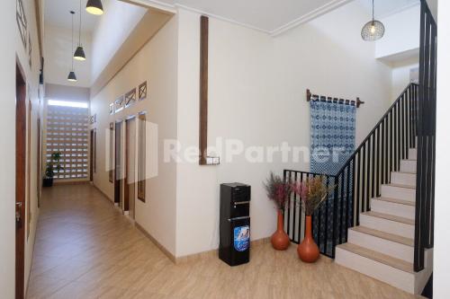 a hallway of a building with stairs and vases at Ndliman House near UGM Jogja Mitra RedDoorz in Kejayan