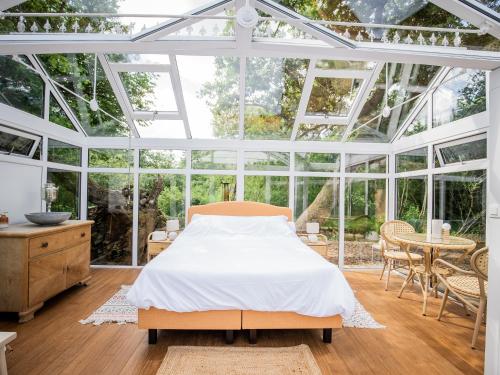 a bedroom with a bed in a glass house at Nids des Marais in Ciney