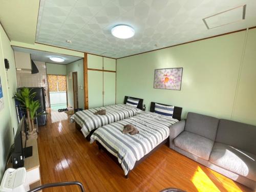 a bedroom with two beds and a couch in it at NAGO Sakura Resort Inn - Vacation STAY 14445v in Nago