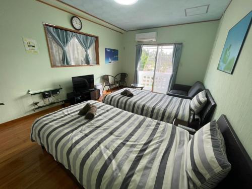 a bedroom with two beds and a couch and a clock at NAGO Sakura Resort Inn - Vacation STAY 14442v in Nago