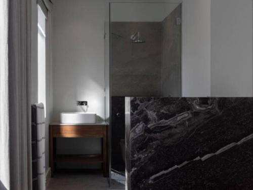a bathroom with a shower with a sink and a desk at Boulders Beach Villa in Simonʼs Town