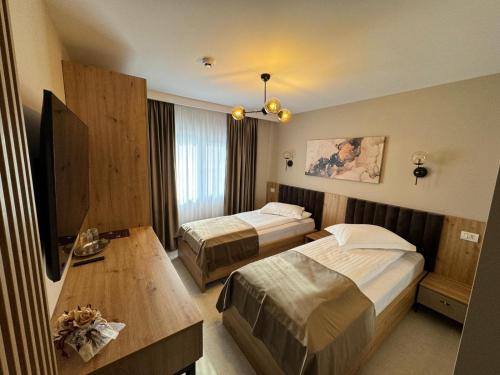 a hotel room with two beds and a table at Pensiune Restaurant Pizzerie 2 Păuni in Borşa