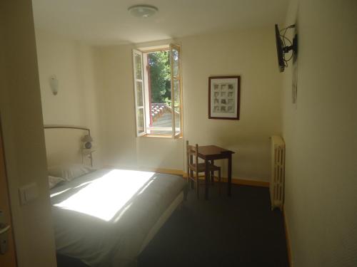 a room with a bed and a table and a window at Logis Hotel Du Champ De Foire in Saint-Aulaye