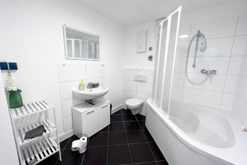 a white bathroom with a sink and a tub and a toilet at Work & stay Langenfeld in Langenfeld