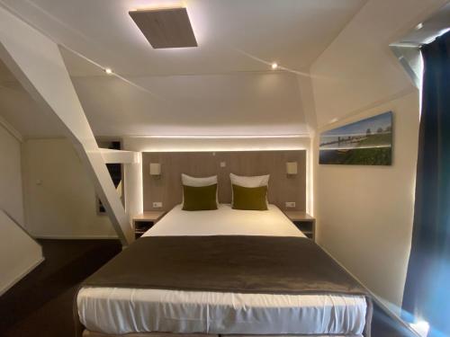 1 dormitorio con 1 cama grande con almohadas verdes en De Twee Linden en Beneden-Leeuwen