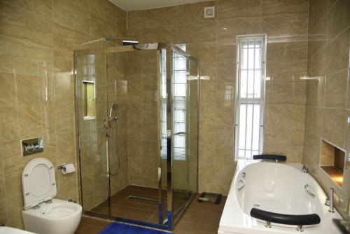 y baño con ducha, aseo y bañera. en EKOH'S PLACE, en Abuja