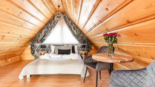 1 dormitorio en una cabaña de madera con 1 cama y 1 mesa en Aparthotel Delta Garden, en Zakopane